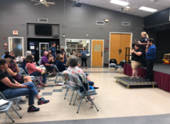 Volunteers talking to an audience in a hall
